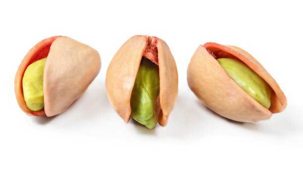 三个红色的土耳其开心果，剥了皮的绿色坚果，在白色的背景上孤立的裂开的壳。图片下载