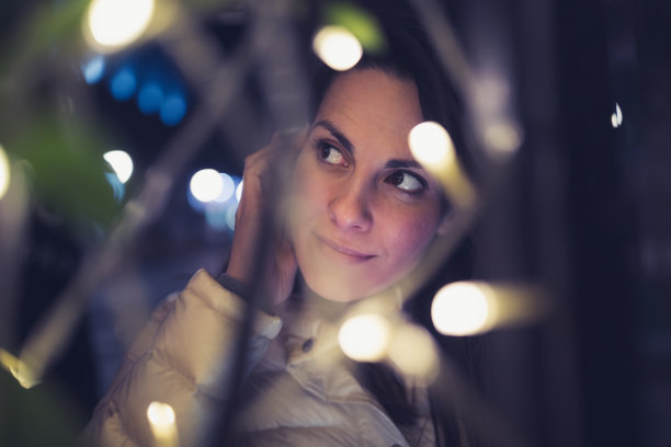 黑发女人，在户外打电话。街上的圣诞彩灯图片下载