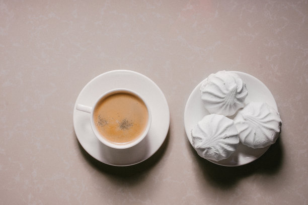 一杯新鲜的咖啡，美式咖啡和三个美味的甜甜点白色棉花糖在碟子上特写。本空间图片下载