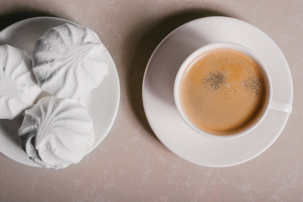 一杯新鲜的咖啡，美式咖啡和三个美味的甜甜点白色棉花糖在碟子上特写。本空间图片下载