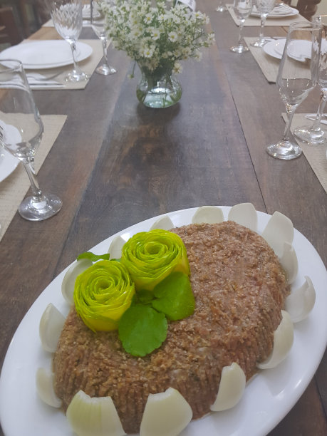 这是一种近似于阿拉伯菜的食物，名字叫生烤肉架，上面装饰着花、洋葱和薄荷形状的西葫芦。桌上的薄碗在背景中模糊不清图片下载