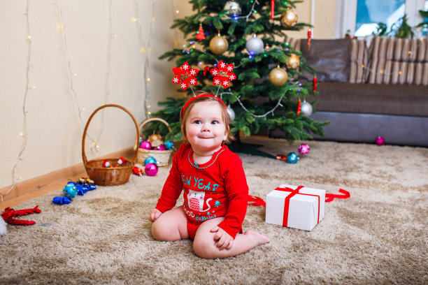婴儿戴红帽子的圣诞照片。新年假期和圣诞树。图片下载