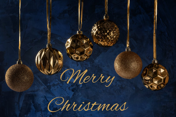 铭文圣诞快乐在深蓝色的背景纹理和装饰腻子。六个金色的圣诞球挂在丝带上。节日的贺卡。图片下载
