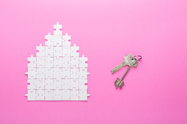 白色的难题。房子形状的拼图和钥匙。租金、抵押的概念。粉红色的背景。俯视图图片下载
