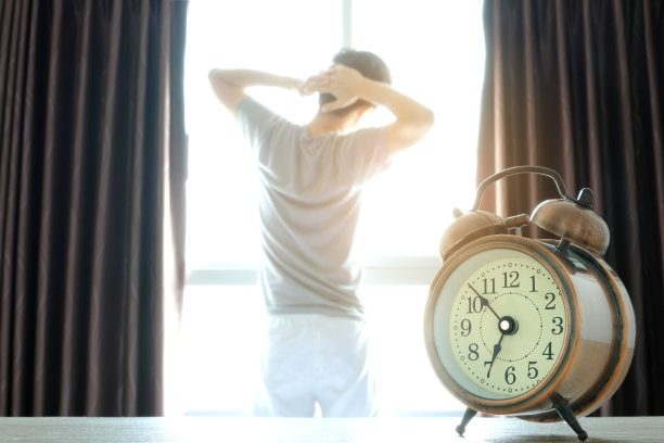 新的一天的早晨，女人在卧室里醒来，她精神焕发。她站在窗口，举起双臂，看着城市的景色，沐浴着阳光图片下载