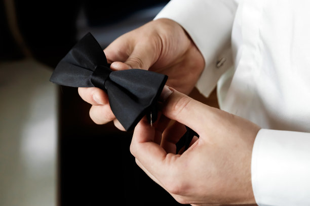 一件白色衬衫配上黑色时髦的大裤子，上面打着蝴蝶蝴蝶结。商人为婚礼戴上袖扣，戴上金手指，亲爱的图片下载