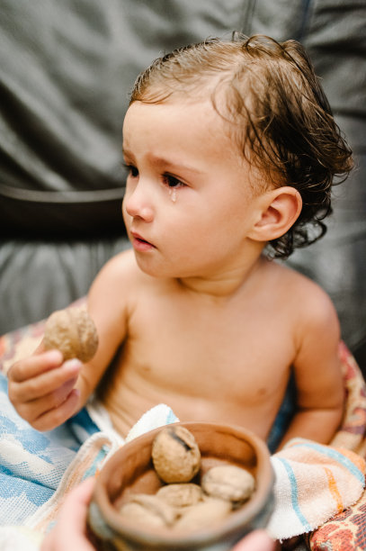 可爱的小女孩吃着坚果，盖着毛巾坐在父母的床上，沙发上，洗澡或淋浴后。清洁干燥的孩子在卧室。概念沐浴和清洗的小孩。图片下载