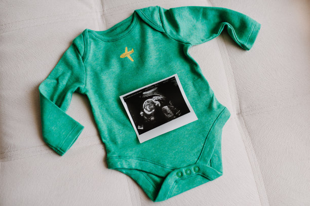 一套婴儿服装，新生儿配件和超声扫描或图片男孩。在家里庆祝怀孕聚会时的问候。后视图。婴儿洗澡。图片下载