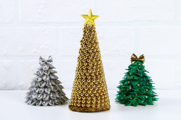 Diy黄金圣诞树的珠子花环。教你如何用硬纸板、星星、热胶和珠子亲手制作圣诞树。手工制作的圣诞装饰。图片下载