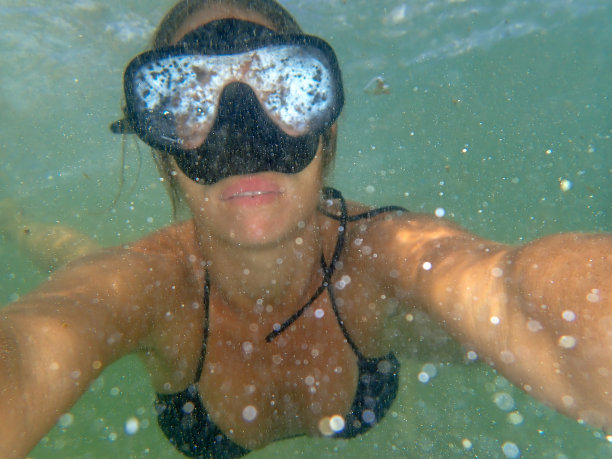 穿着黑色比基尼和潜水面罩在水下游泳的美丽女人图片下载