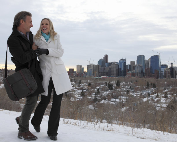 一对商务夫妇在雪中行走在城市上空图片下载