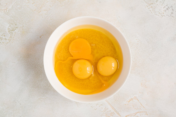 面团烹饪-在一个白色的碗里加入鸡蛋和糖和黄油，俯视图图片下载