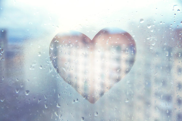蓝色的心画在城市的玻璃湿窗上图片下载