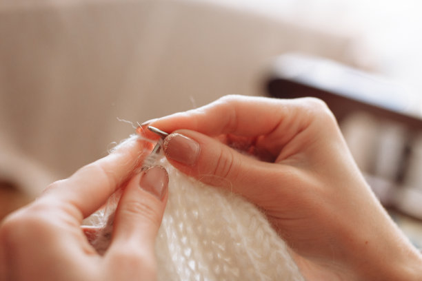 女人用手编织天然羊毛衣服。编织针特写。水平的照片。自由创造性的工作。手工艺的概念图片下载