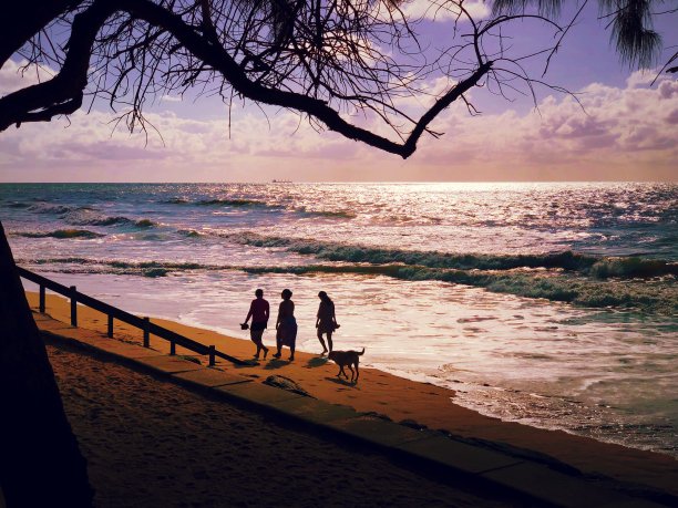 夕阳西下，一家人在海滩上散步。图片下载