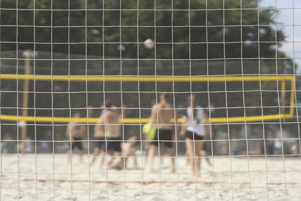 一群年轻的朋友在沙滩上玩排球，有选择性的集中。模糊的背景，健康的生活方式图片下载