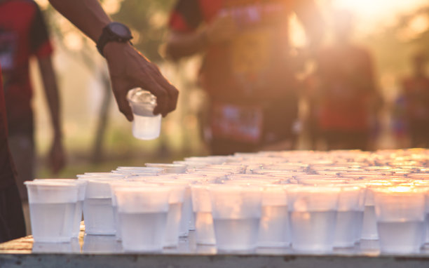 在日出、选择性聚焦、浅DoF条件下，马拉松运动员在服务点饮水图片下载