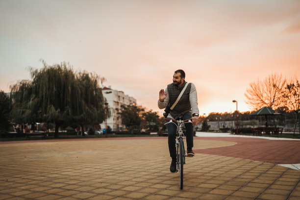 在一个阳光明媚的日子里，一个快乐的人在公园里骑自行车图片下载