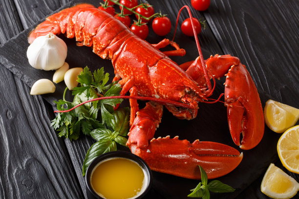 新鲜准备的龙虾特写，柠檬，大蒜，新鲜的西红柿和香草在桌子上。水平图片下载