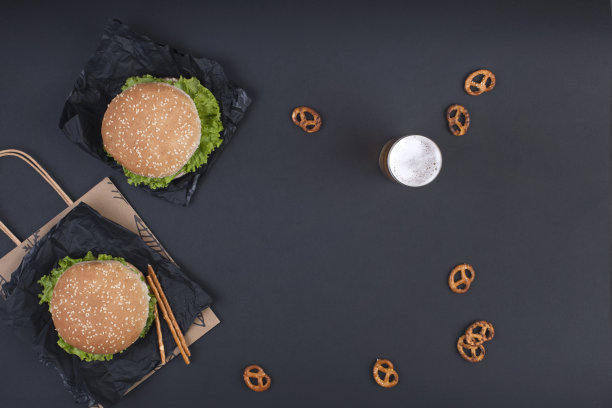 黑色背景下的两个汉堡做午餐。快餐和零食。文本的空闲空间。副本的空间。平的。图片下载