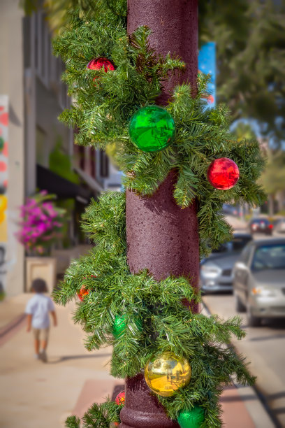 圣诞节绿色的花环环绕着街道灯杆，上面覆盖着五颜六色的小球。图片下载