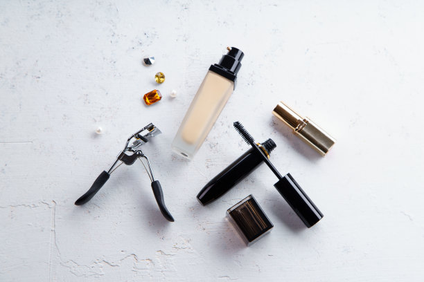 化妆品俯视图图片:口红，粉底，睫毛膏和睫毛夹上纹理的石头背景。化妆师套装概念图片下载