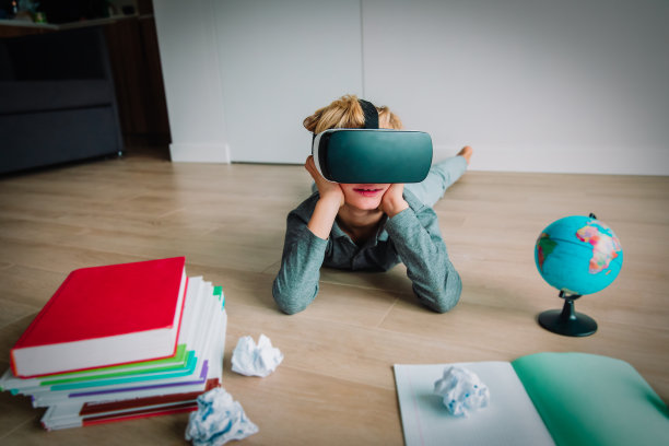 小男孩戴着虚拟现实头盔在家做作业图片下载