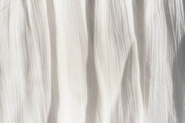 织物背景纹理。白色薄织物，垂直皱褶不均匀，阳光下有阴影图片下载