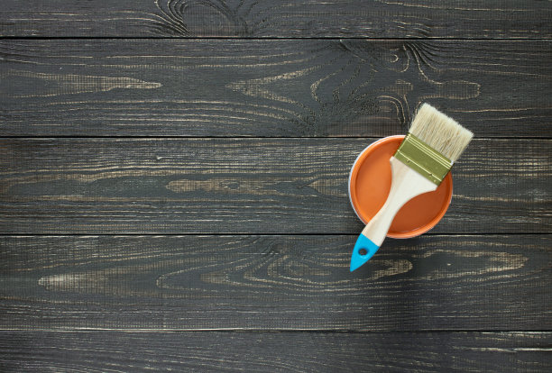 刷子和油漆罐在深色的木制背景上图片下载