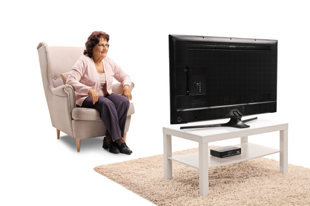 坐在扶手椅上看电视的老妇人图片下载