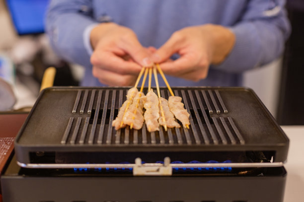 一个坐在烤肉串上的男人，特写图片下载