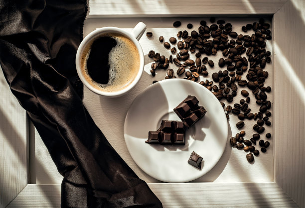 一杯咖啡，咖啡豆和黑巧克力放在白色的盘子上，背景是白色的图片下载