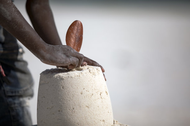 非洲小男孩把旗帜插在沙堡上图片下载