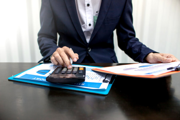 商人使用计算器计算企业的营业额。图片下载
