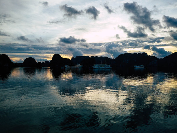 下龙湾的日出。用蓝色和橙色调。背景中有一些船。越南。图片下载