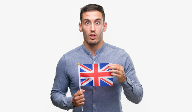 英俊的年轻人举着英国国旗吓得脸上带着惊讶、害怕和兴奋的恐惧表情图片下载