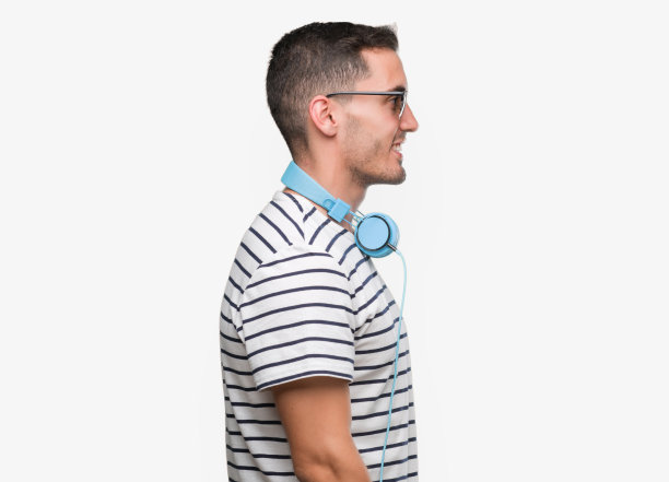 英俊的年轻人戴着耳机看向一边，放松的侧面姿势，自然的脸上带着自信的微笑。图片下载