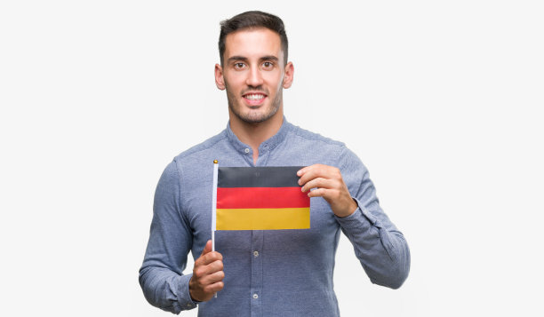 英俊的年轻人举着德国国旗，面带笑脸站在那里，自信地微笑着露出牙齿图片下载