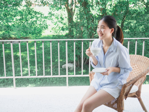 亚洲女性在阳台上喝咖啡图片下载