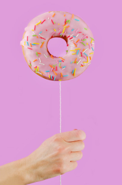 粉色背景上拿着甜甜圈图片下载