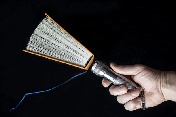 打开书和手电在人的手里。图片下载