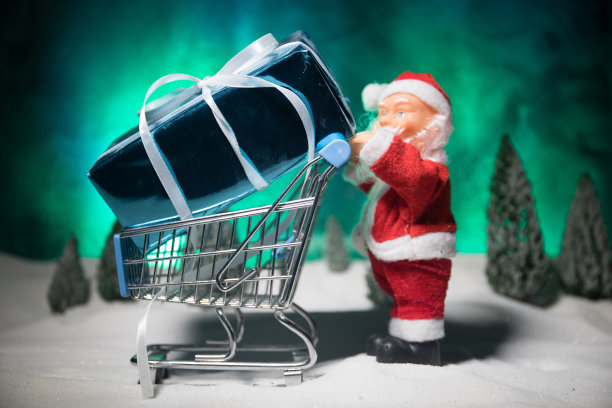 新年或圣诞节购物概念。商店促销活动。圣诞老人推着小推车在雪地上行走图片下载