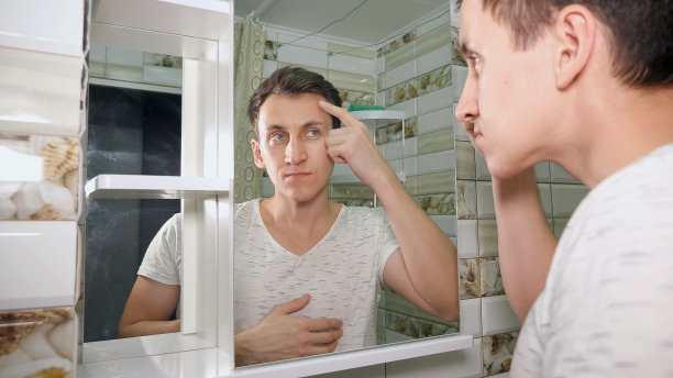 一个年轻人在浴室里检查自己的皮肤图片下载