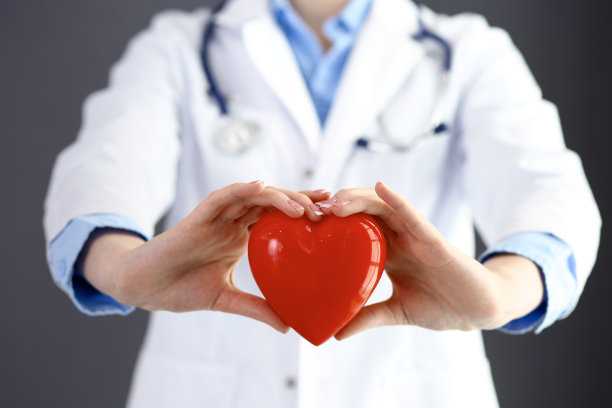 女医生用听诊器抱着心脏。医学中的保健和心脏病学概念图片下载
