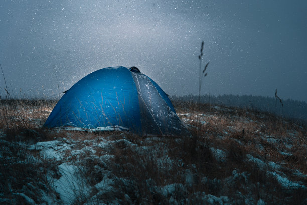 晚上，一个蓝色的帐篷立在田野里。下雪了。图片下载