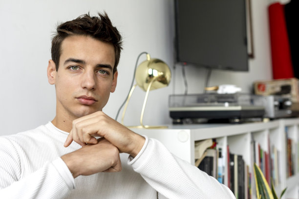 一个坐在沙发上看着镜头的年轻帅哥的肖像图片下载