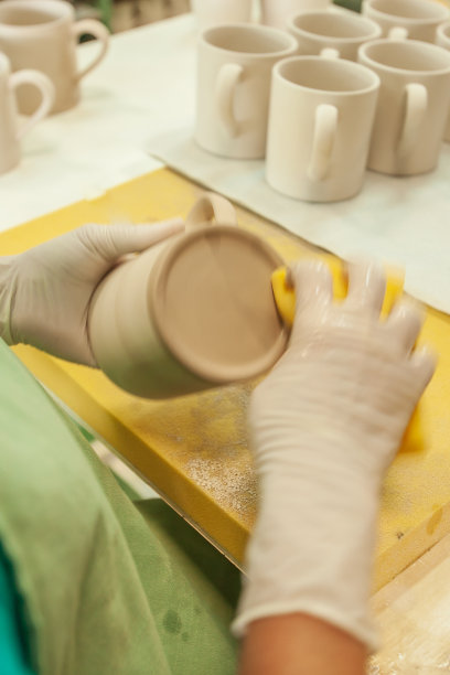 泰国工匠清洗白色陶瓷杯上的黄色架，陶瓷是泰国南邦省的产品，地方和国家级别一样。长时间的曝光。柔和的光。图片下载