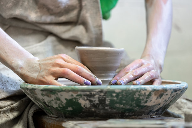 大师班的概念。裁剪近距离照片的工艺女士在她的肮脏的工作，她坐在工作区内使用圆形陶瓷车轮做小杯子图片下载