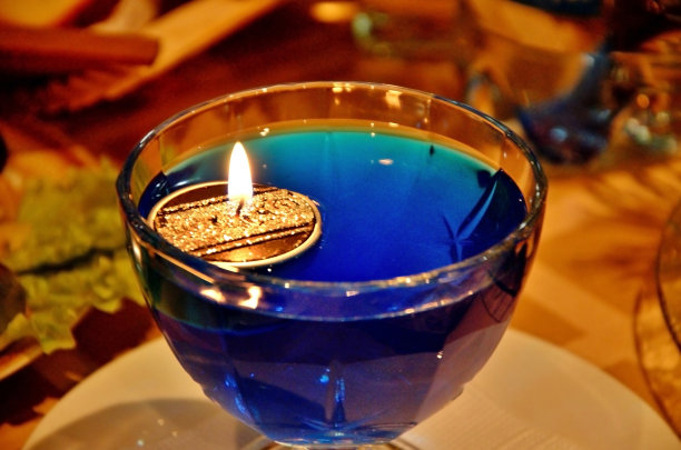 蜡烛与火漂浮在一个玻璃容器与蓝色的水。新年餐桌的装饰图片下载