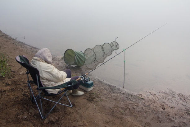 河上的早晨。渔妇睡在折叠椅上图片下载